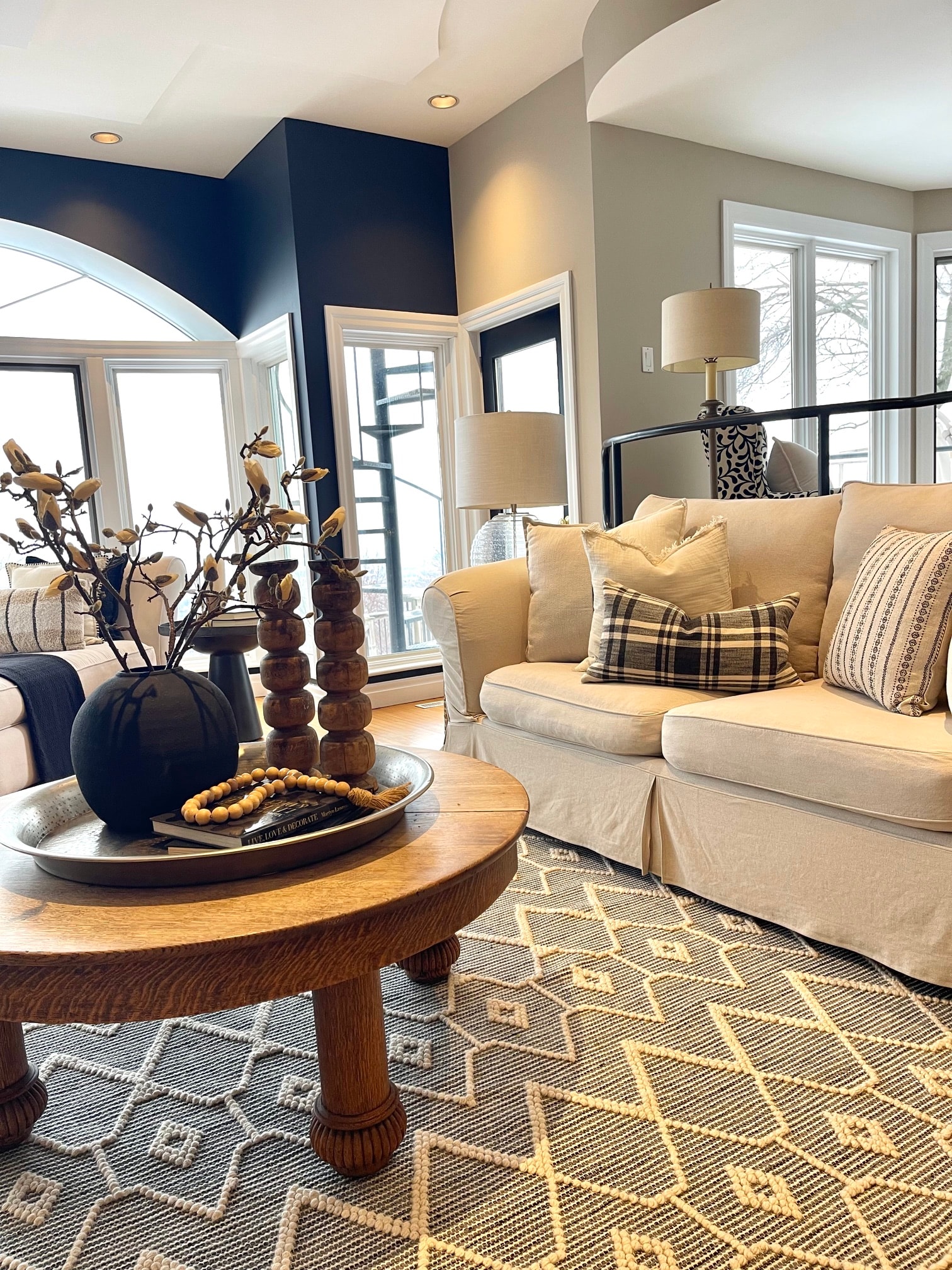 A warmly staged living room with a navy accent wall, cream sofa, and layered textiles