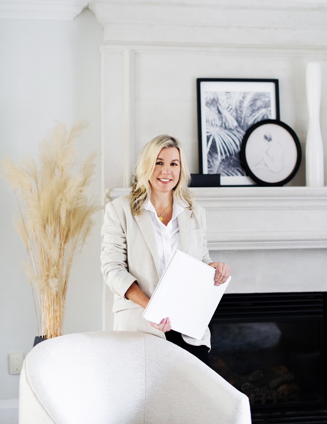 Jennifer Moore, founder of Birch and Co Home Staging, standing beside a fireplace mantel