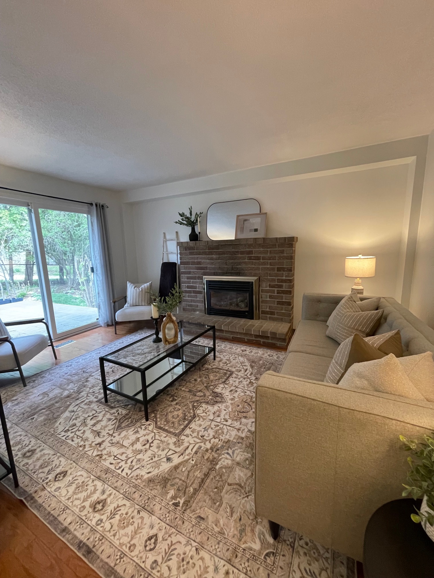 Same living room after staging, with a sofa, styled mantel, and layered decor