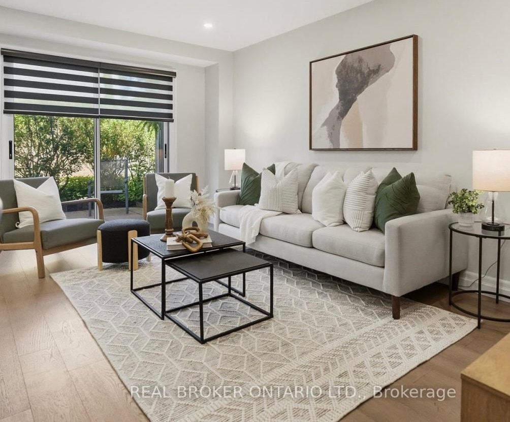 Same living room after staging, with a sofa, patterned rug, and layered decor