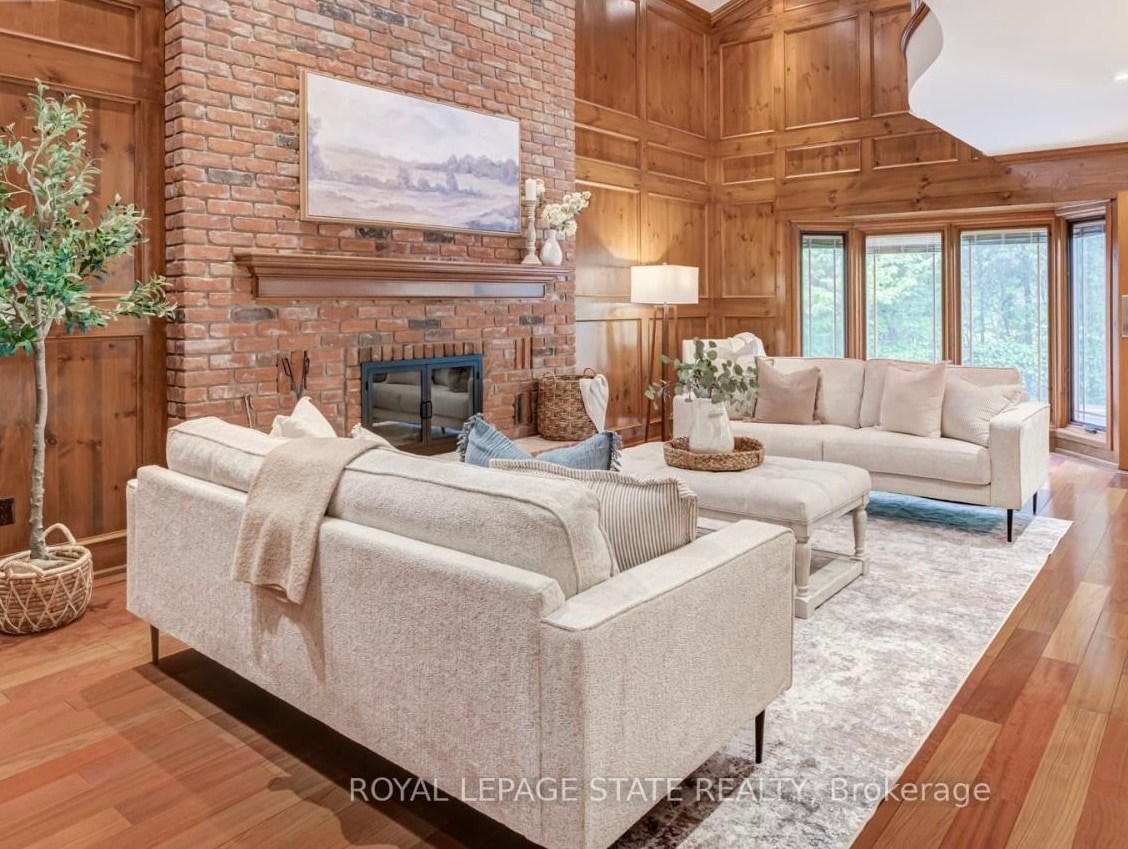 Same living room after staging, with two cream sofas and a styled fireplace mantel
