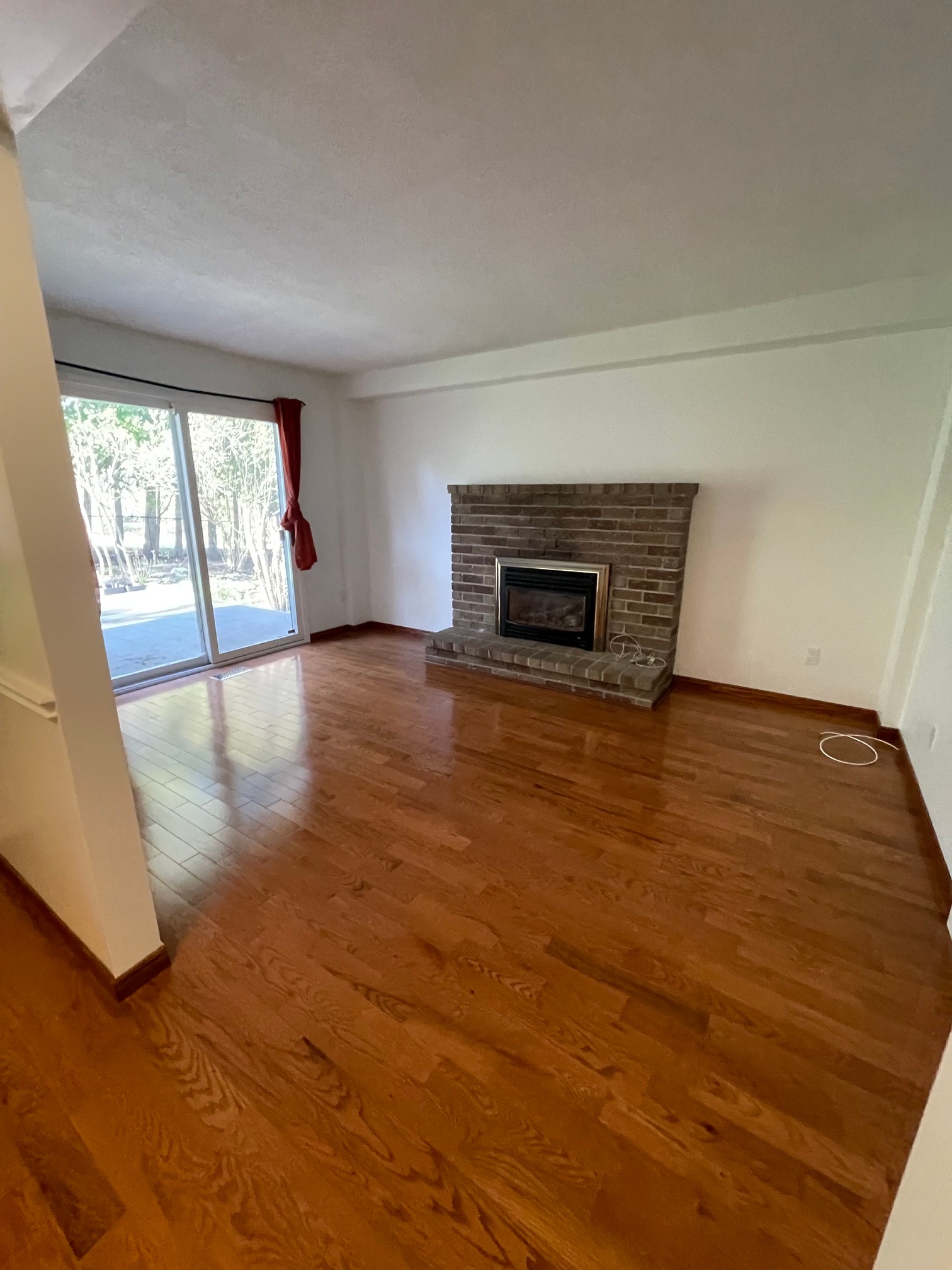 Living room with a brick fireplace before staging, unfurnished