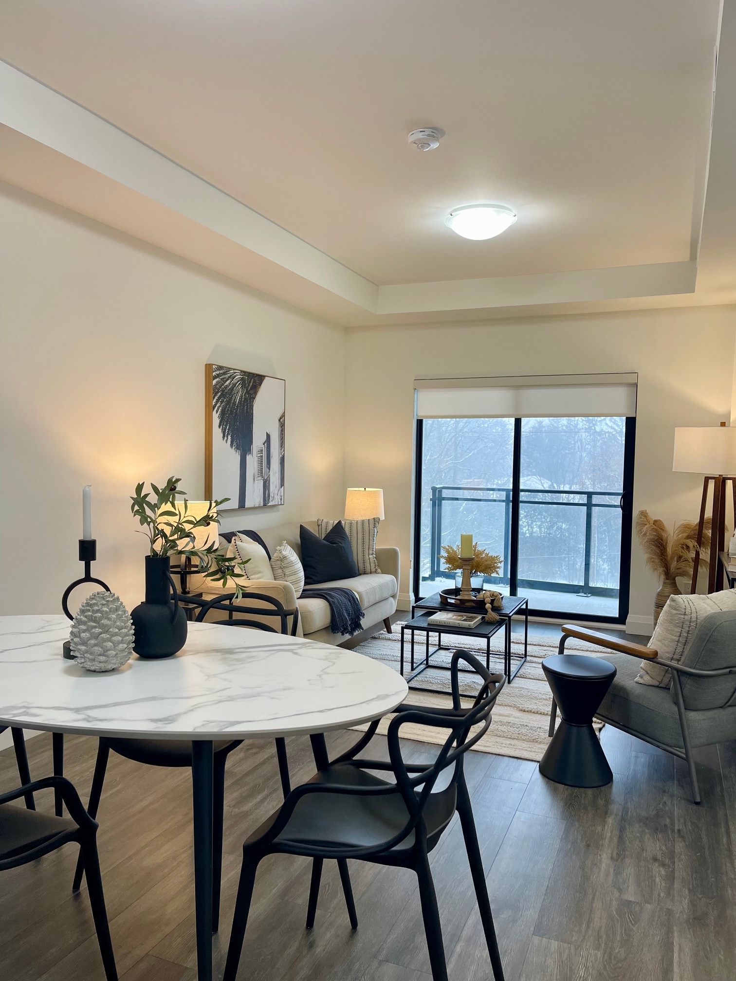 Same condo after staging, with a dining table, living area, and balcony view