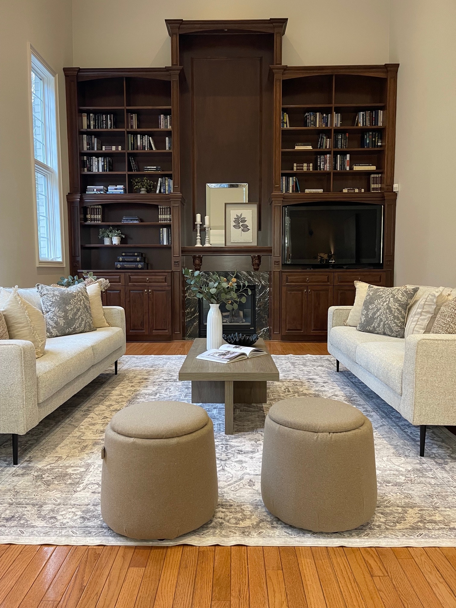 Same living room after staging, with facing sofas and a styled fireplace mantel