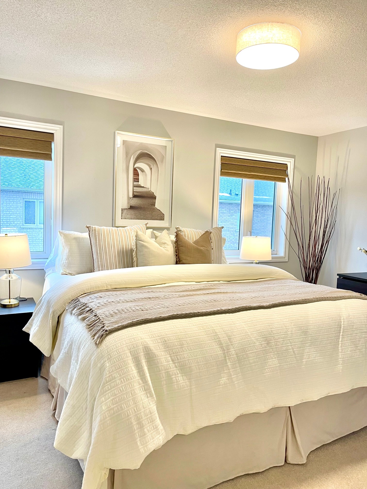 Warm, inviting bedroom styled with layered pillows, soft lighting, and natural greenery
