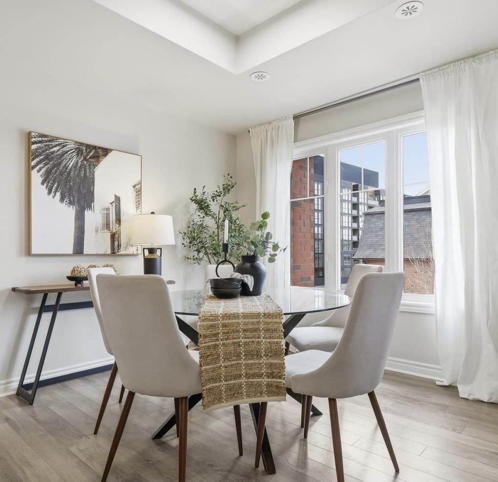 Bright, styled condo dining area with a round glass table and palm tree artwork
