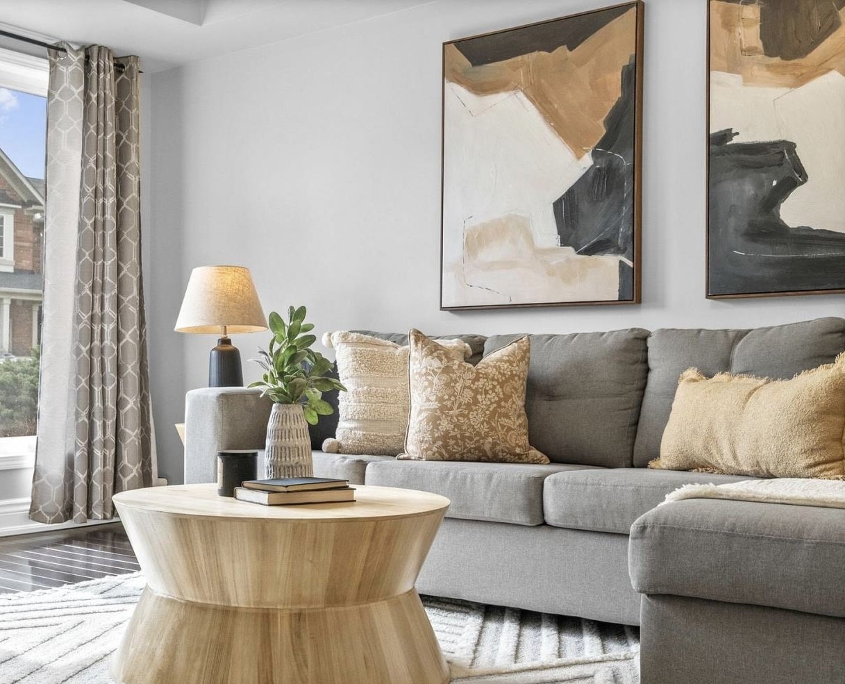 Elegant living room styled with a grey sofa, warm patterned pillows, and bold abstract artwork